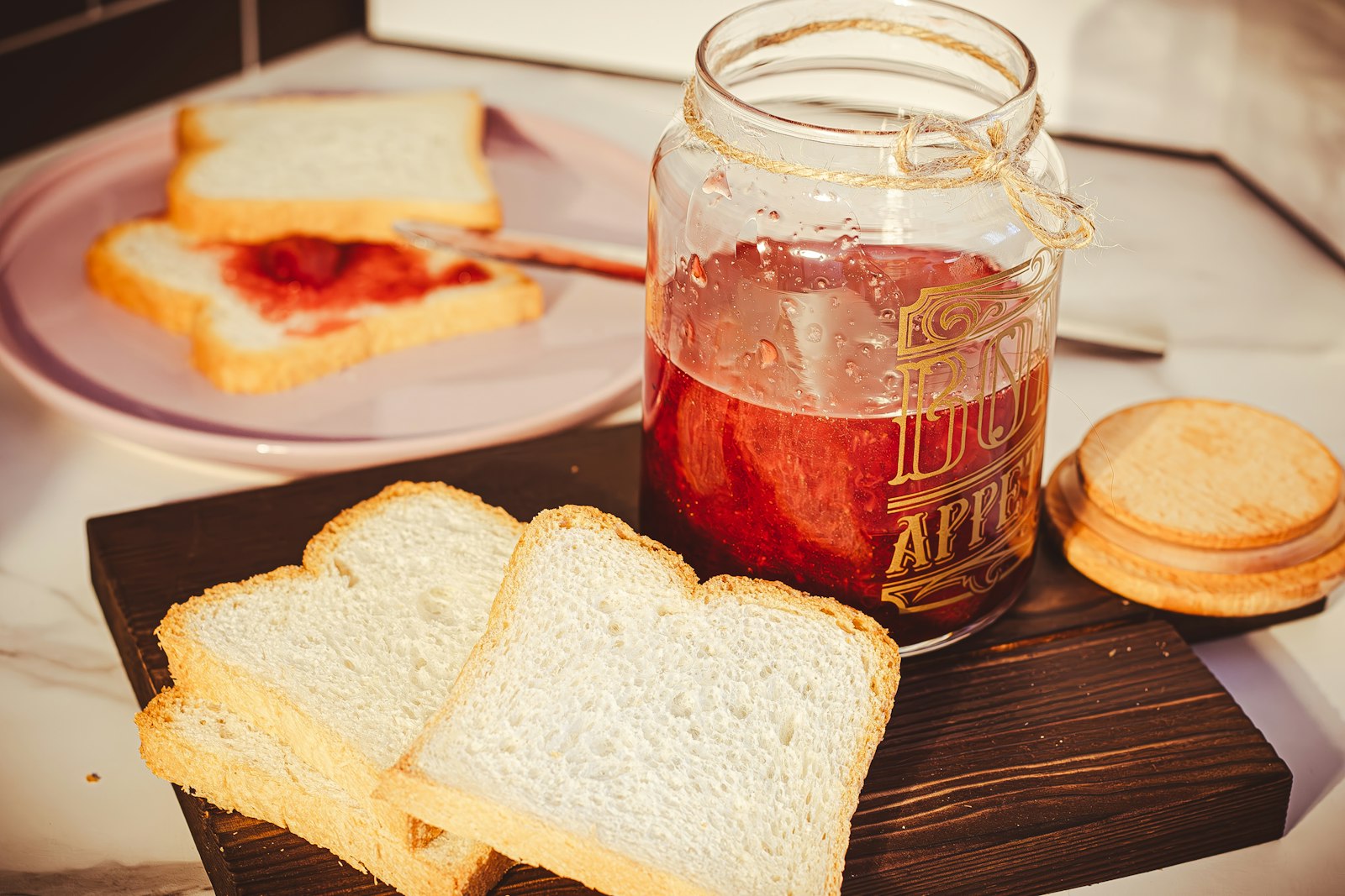 A jar of jelly and slices of bread on a cutting board