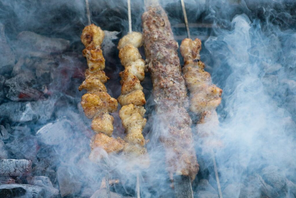 Several skewers of food being cooked on a grill
