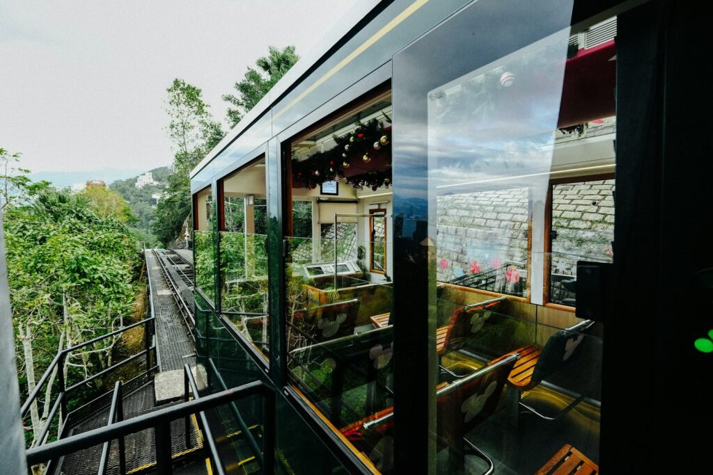 Modern tram car with glass windows ascending a green hillside