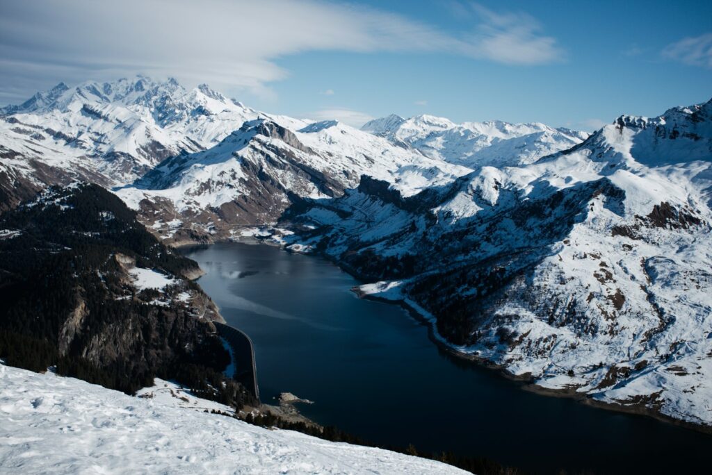 Snow-covered mountains surround a dark, calm lake