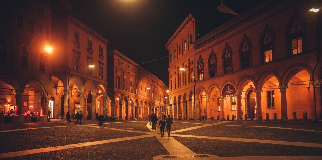 Arched buildings line a cobblestone square at night