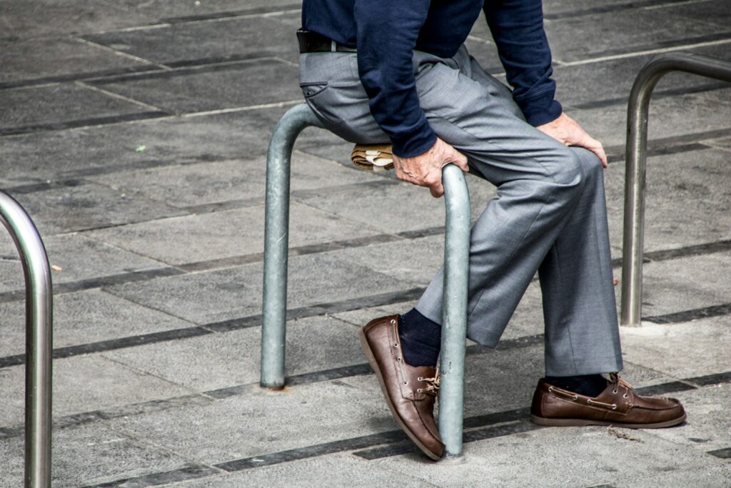 Man sitting on gray metal roll bar on gray pavement