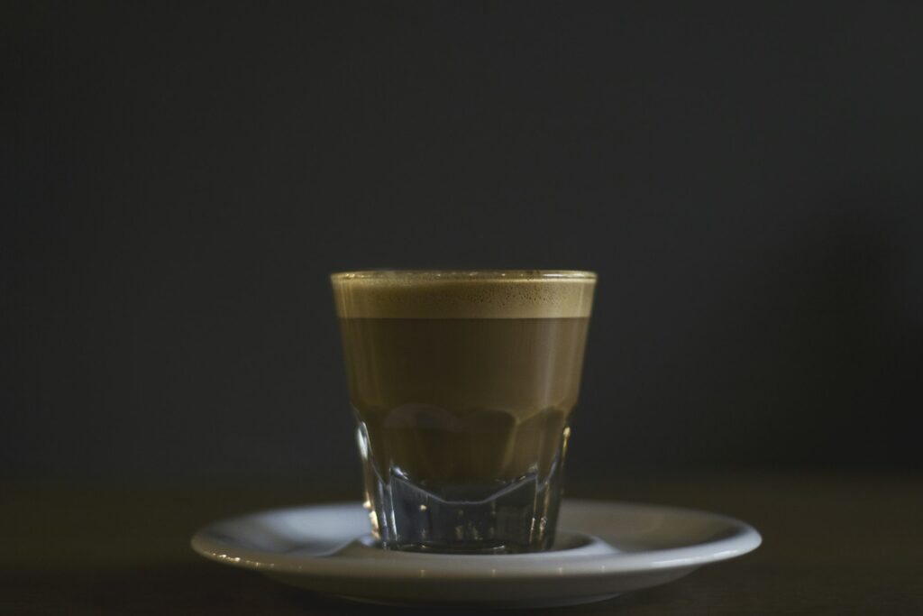 Coffee filled rock glass on saucer