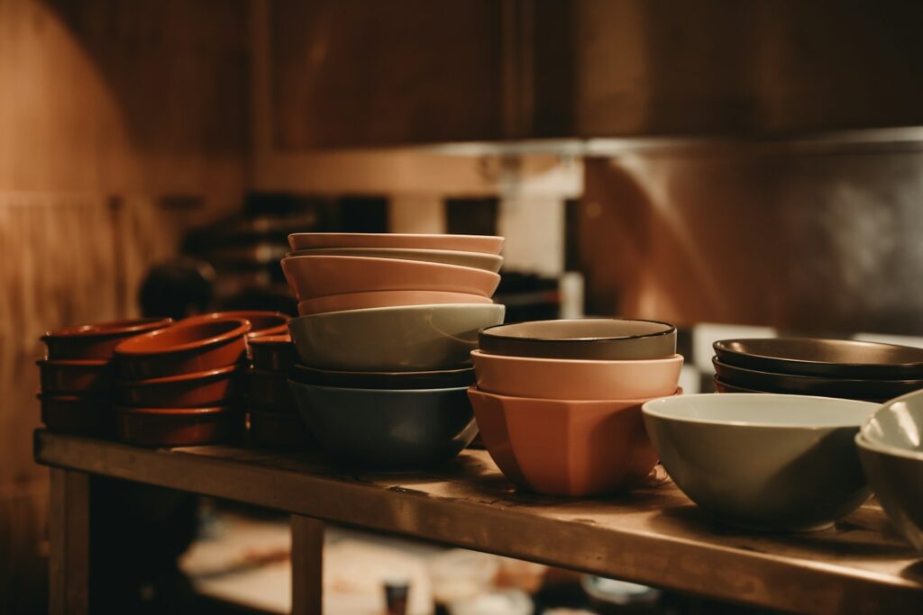 Stacks of colorful ceramic bowls on a wooden shelf