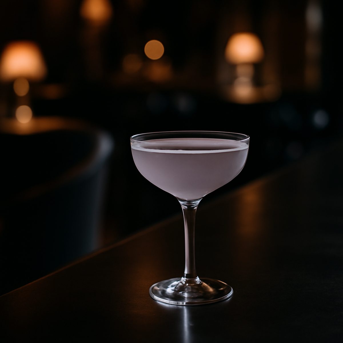 Pale violet Aviation cocktail in a coupe glass on a dark bar counter